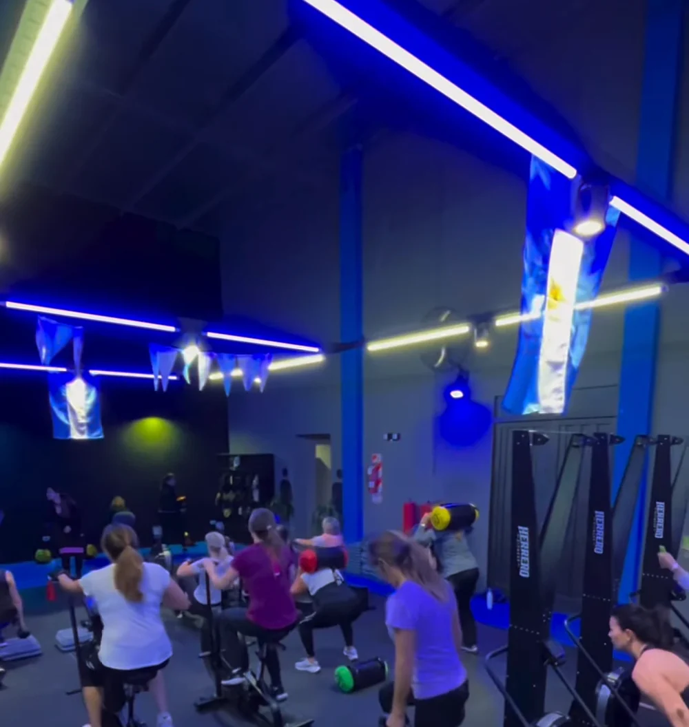 Salón de Body Global, luces lineales azules y clase en entrenamiento